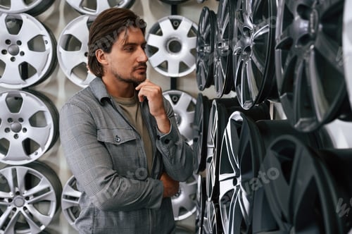 Preview: Thinking, choosing. Man is in the tire fitting car service