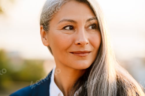 Preview: Mature asian businesswoman wearing suit smiling and looking aside