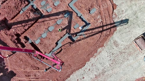 Preview: House foundation is being filled with wet concrete by builder using a concrete pump.
