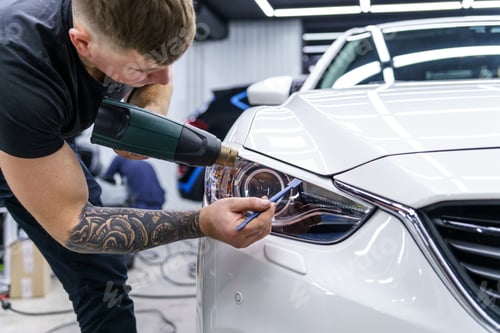Preview: Sticker of a protective film on the headlight of a car in a car detailing studio