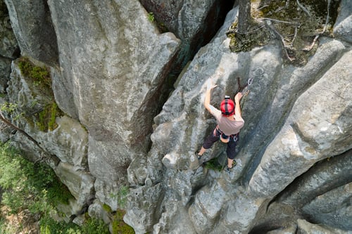 Preview: Strong male climber climbing steep wall of rocky mountain
