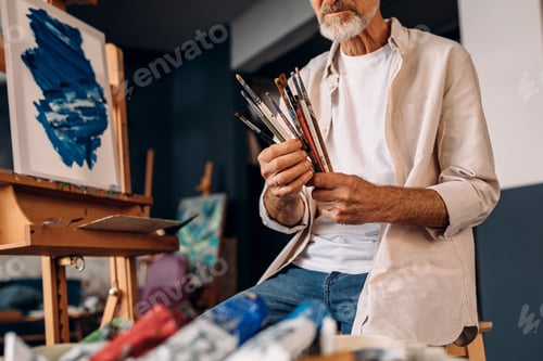 Preview: Man working as painter checking brushes before painting