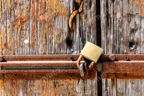 Preview: Rusty padlock mounted on an old, weathered wooden door, close up