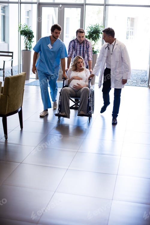 Preview: Male doctor talking to pregnant woman in wheelchair