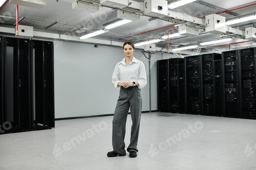 Preview: A woman in a white shirt stands in a sleek, modern server room, focused on her tasks.