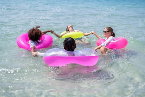 Preview: Teenage girl friendship enjoy laughing play on sea swimming with water inflation toy on blue sky day