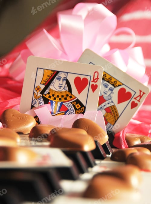 Preview: Love concept. King and Queen of hearts playing cards together on piano keys with chocolate and