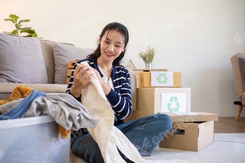 Preview: A young woman separates unused clothes and prepares them for donation or recycling in order to