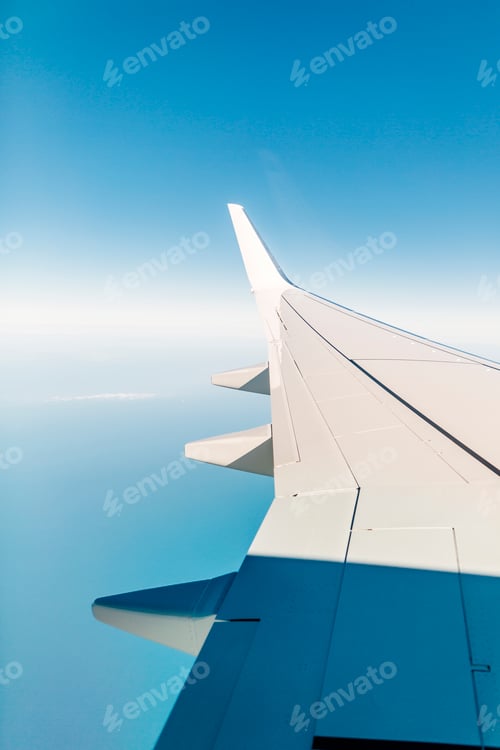 Preview: Cropped image of airplane wing against blue sky