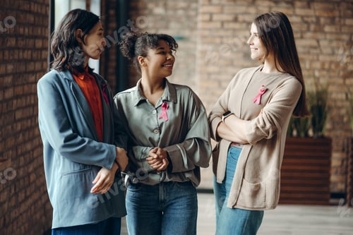 Preview: Diverse women showing support for breast cancer awareness with pink ribbons