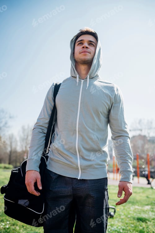 Preview: Calisthenics at outdoor gym, young man carrying sports bag