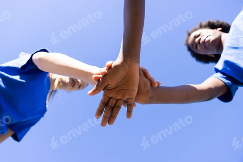 Preview: Holding hands, diverse girls in blue shirts forming unity at school event