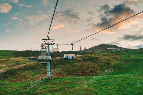 Preview: Chairlift or cable car lifting over Stoos village and Swiss Alps mountain in the evening