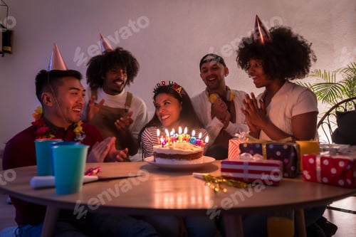 Preview: Multi-ethnic group of friends at a birthday party on the sofa at home with a cake and gifts