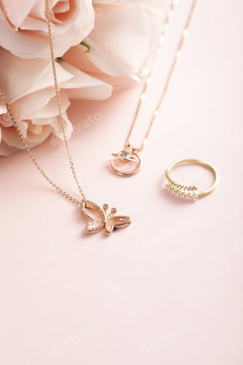 Preview: Vertical shot of a beautiful ring and necklaces on a pink surface