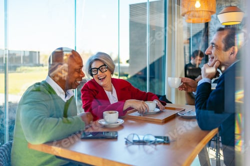 Preview: Group of friends chatting and laughing over coffee in a cozy cafe setting