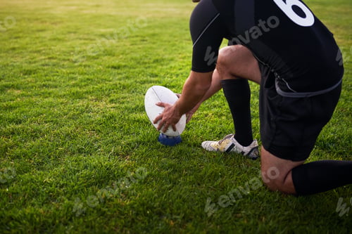 Preview: Cropped shot of an unrecognizable sportsman crouching alone during rugby practice in a sports club