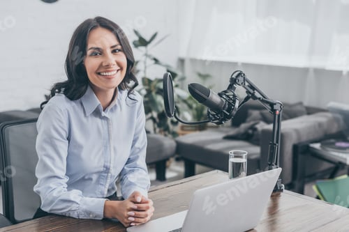 Preview: smiling radio host sitting at workplace near microphone and looking at camera