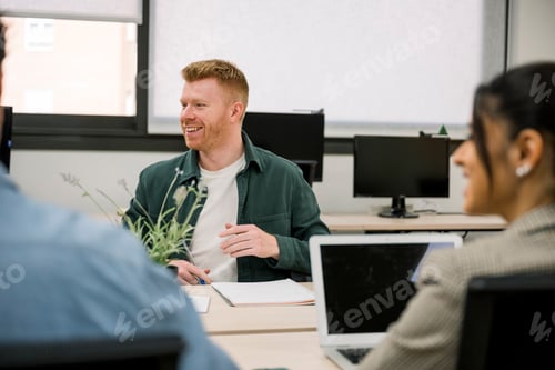 Preview: Smiling man collaborating with diverse colleagues in modern office meeting