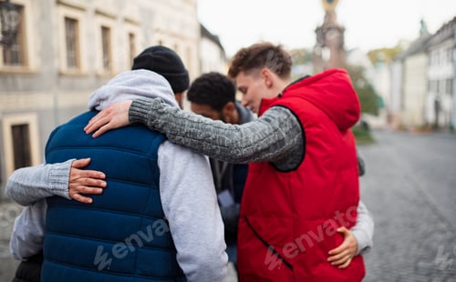 Preview: Rear view of community service volunteers hugging together outdoors in street