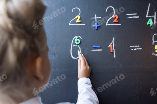 Preview: cropped shot of little schoolgirl drawing numbers on chalkboard