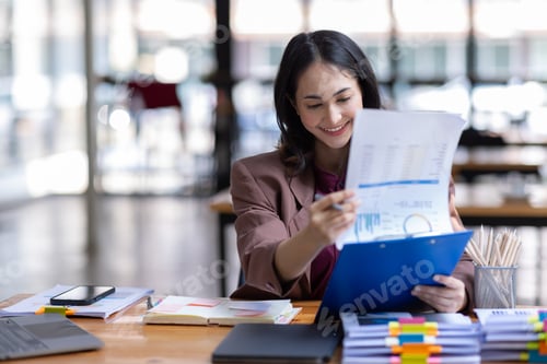 Preview: Freelancer Happy business Asian woman in knitwear taking notes at laptop sitting at desk office,