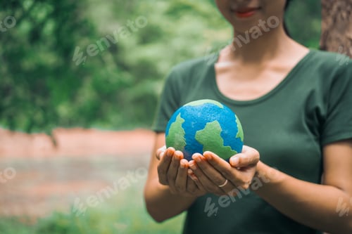 Preview: An Asian woman holds a globe in green forest,symbolizing importance preserving nature.emphasizes