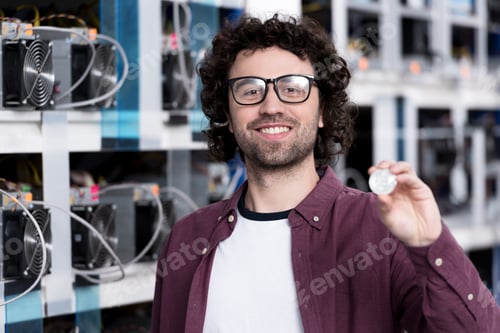 Preview: young computer engineer holding bitcoin at cryptocurrency mining farm