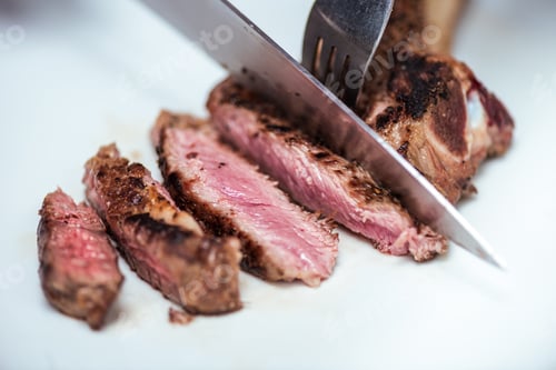 Preview: cropped image of chef cutting fried meat with knife and fork