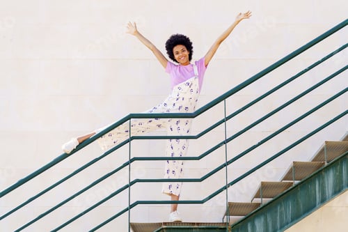 Preview: Happy black woman raising leg on railing