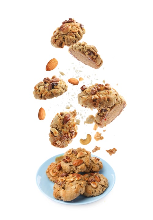 Preview: Yummy nut cookies falling onto plate on white background