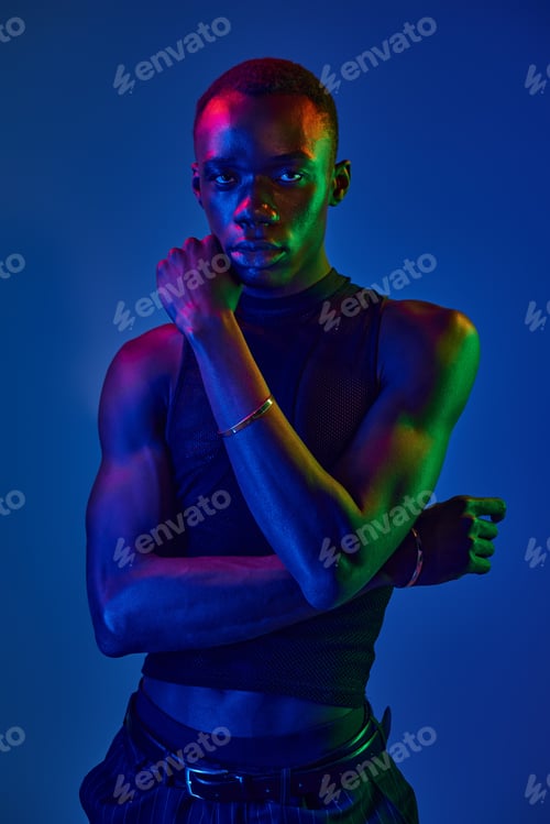 Preview: Vibrant young man showcases stylish attire in a dynamic color backdrop