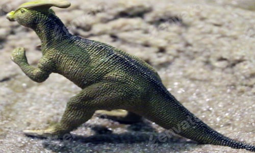 Preview: Minimalist image of child’s green toy dinosaur on sand.