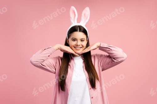 Preview: Cheerful brunette girl wearing bunny ears headband and holding hands near chin