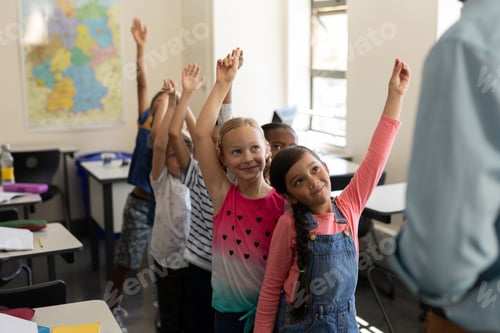 Preview: School kids standing in row and raising hand in classroom of elementary school
