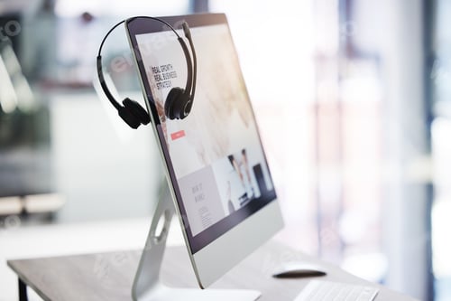 Preview: Closeup of headset hanging on a computer desktop monitor in an empty call centre office. Operating