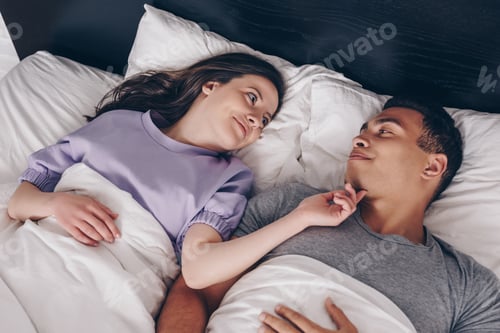 Preview: overhead view of cheerful woman touching mixed race boyfriend in bed