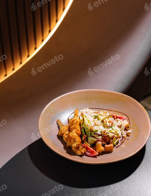 Preview: Delicious caesar salad with chicken skewers served on plate in restaurant
