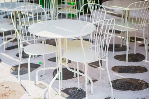 Preview: White tables with chairs at summer empty open air cafe in Greece