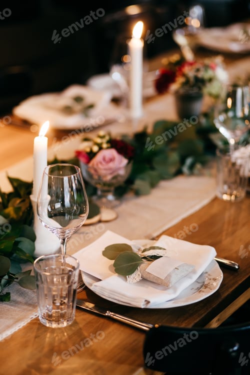 Preview: Plates, candles, knives, forks on wooden table decorated with branches of greenery