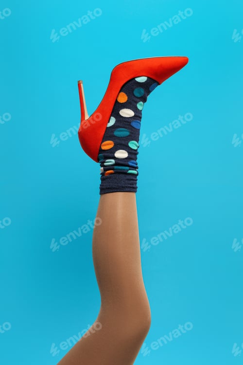 Preview: Woman wearing sock and high heel shoe on light blue background, closeup