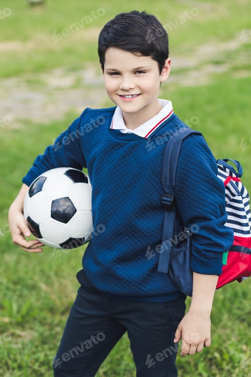 Preview: cute kid with soccer ball with soccer ball and backpack on grass field