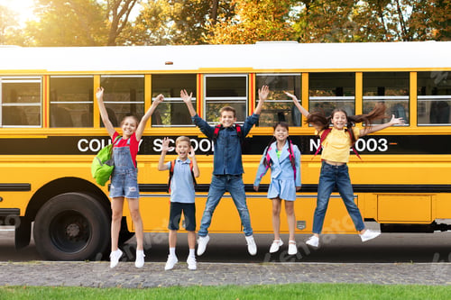 Preview: Group of happy kids jumping in front of school bus outdoors