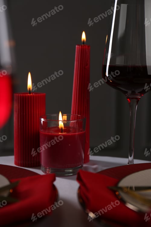 Preview: Place setting with red candles on white table. Romantic dinner