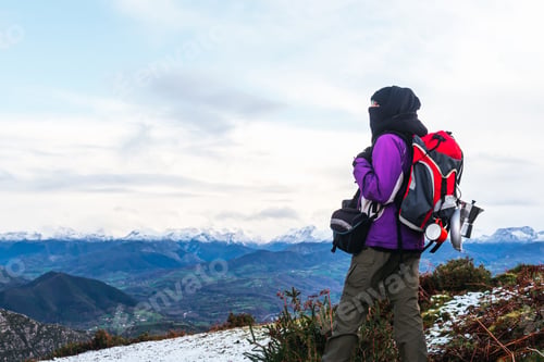 Adventurous Woman Hiking in Mountains with Snowy Peaks