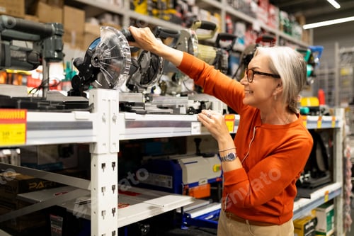 Preview: Woman selects tools in a hardware store during a busy shopping day