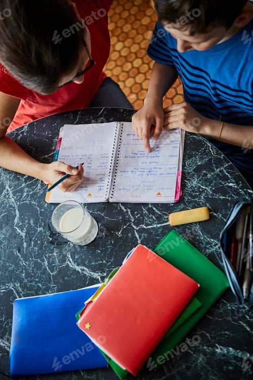 Preview: High angle view of mother and son at dining table doing homework