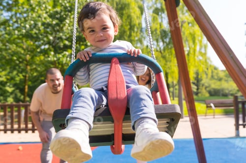 Preview: Parents swinging a small child at the playground