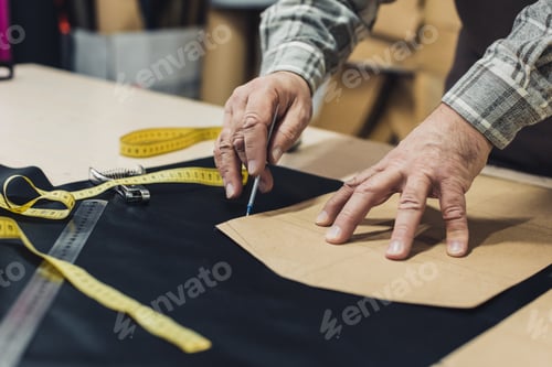 Preview: cropped image of male leather handbag craftsman working at studio