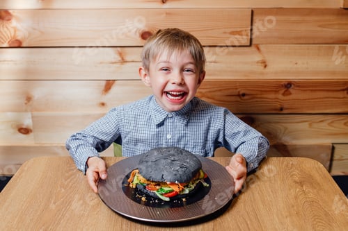 Preview: Excited Boy With Unusual Black Burger at Table